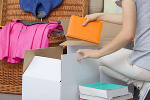 26312829 l A woman packing colorful books into a cradboard box 1024x683 1